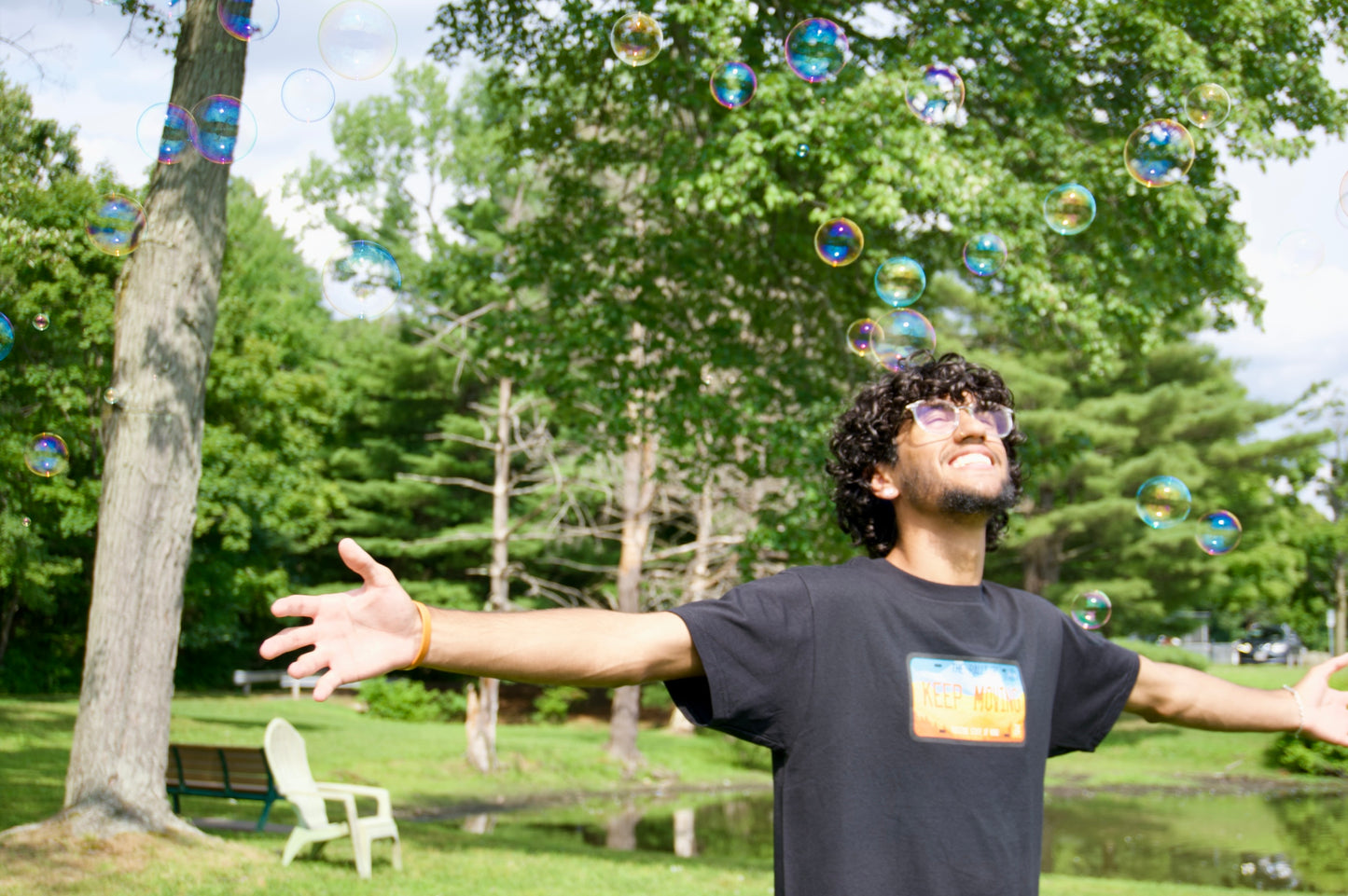 Black tee being worn while running through bubbles, smiling. 