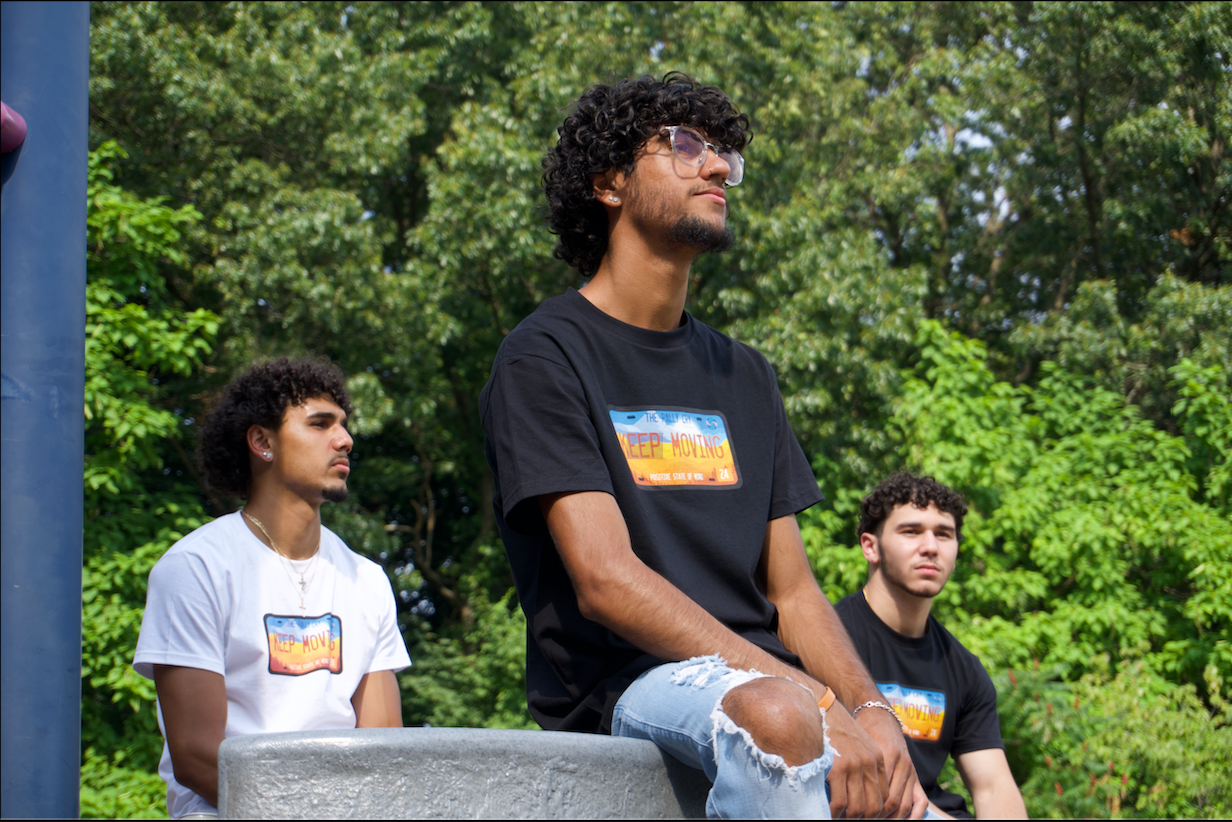 three men siting down looking out in a distance wearing keep moving tees